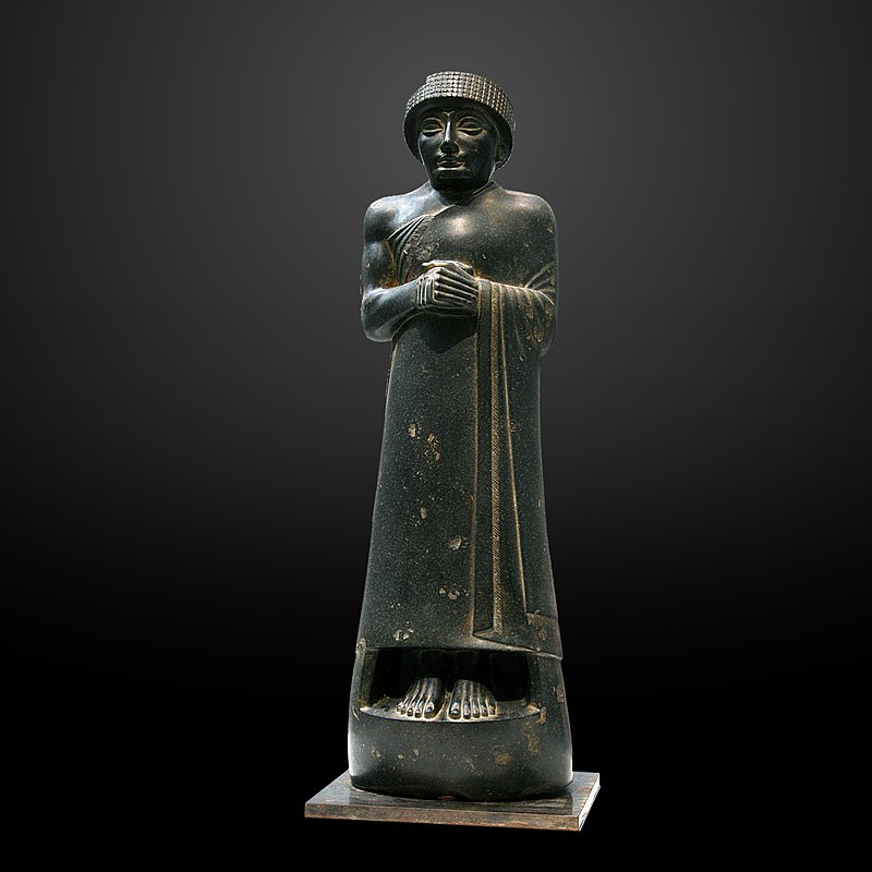 A dark stone statue of an ancient Mesopotamian ruler